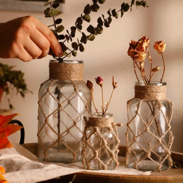 Decorative glass jars with twine wrapping on a wooden surface.