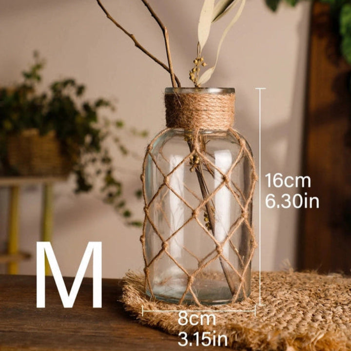 Glass vase with woven top on a wooden surface, featuring measurements and brand logo.