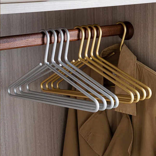 Gold and silver aluminium clothes hangers on wooden rail, minimalist slimline design for modern wardrobe organisation.