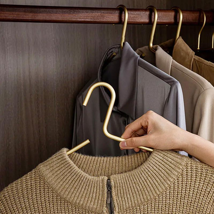 Gold aluminium hanger holding a beige knit jumper, smooth surface prevents fabric damage in stylish wardrobe display.