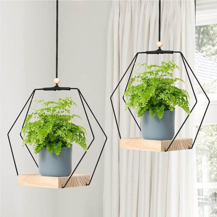 Set of two hanging wooden plant holders with black geometric frames, styled with potted ferns in grey planters for Nordic-inspired home decoration.