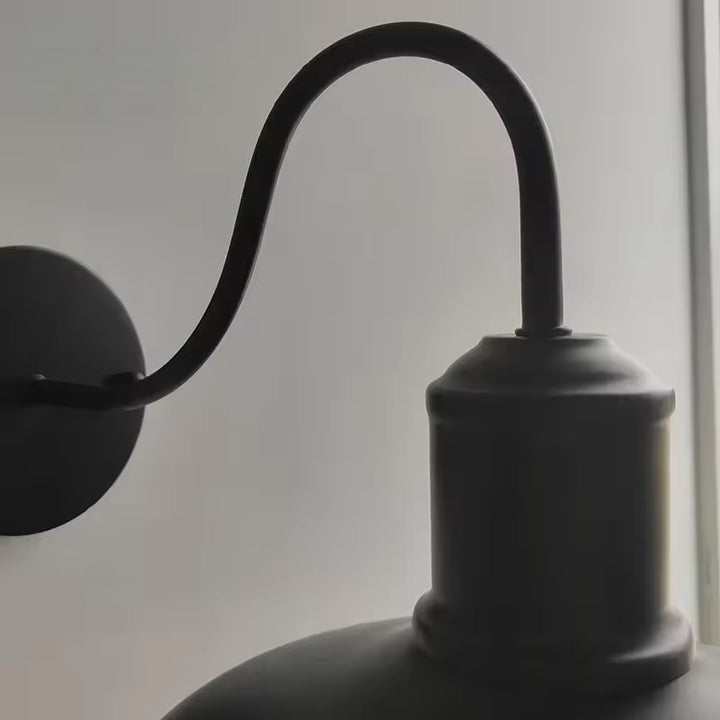 Close-up of curved black arm and fixture detail of retro outdoor industrial wall lamp