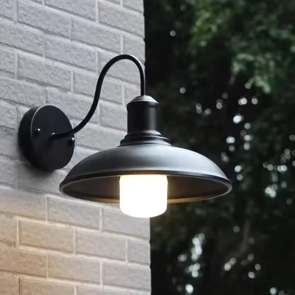 Black retro industrial outdoor wall light illuminated in heavy rain, waterproof LED fixture mounted on tiled exterior wall