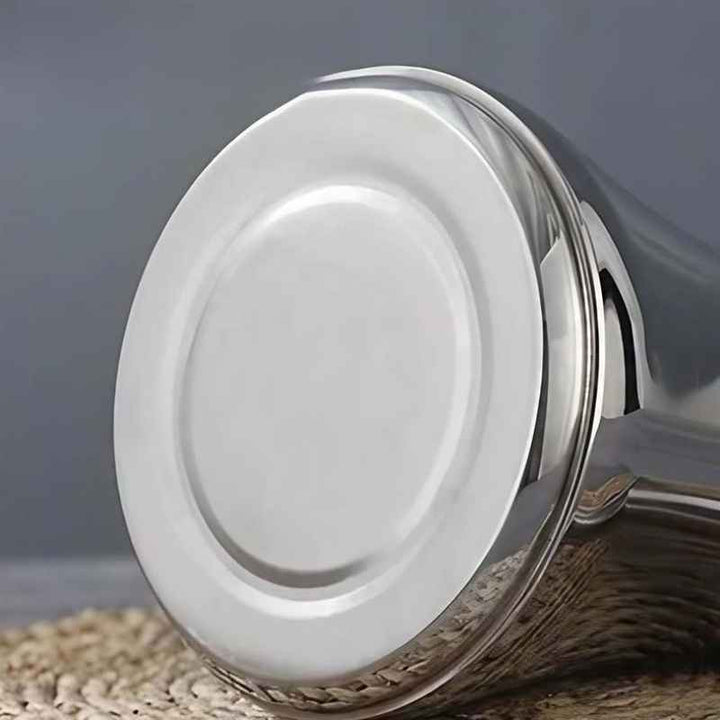 Close-up of a Silver stainless steel induction kettle with a reflective surface on a textured surface.