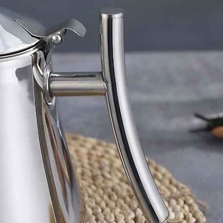 Close-up of a shiny Silver stainless steel induction teapot handle on a textured surface with a blurred background