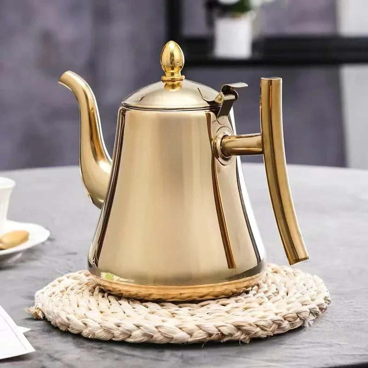 Gold induction coffee pot on a woven coaster with a blurred background