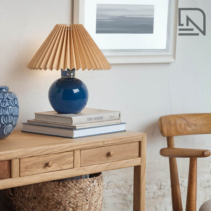 Blue pleated shade table lamp on wooden bedside table, Scandinavian lighting for modern bedrooms.