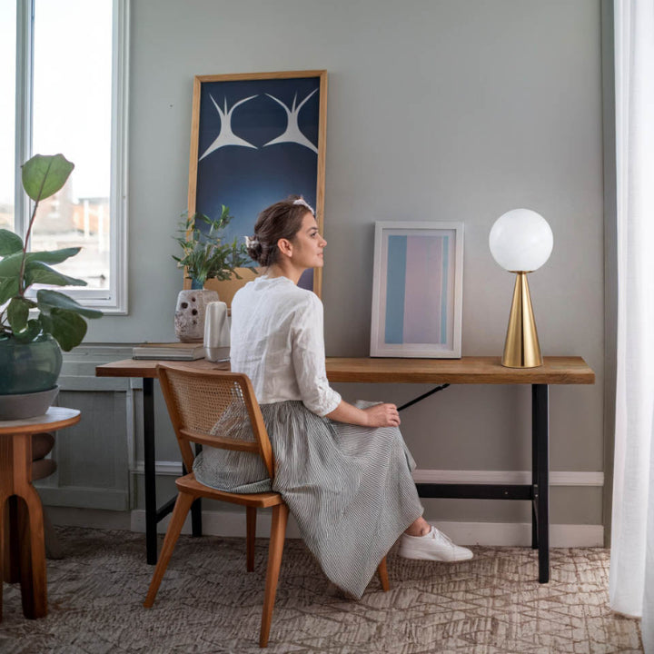 Brass globe table lamp on writing desk, providing soft ambient light for reading or working from home.
