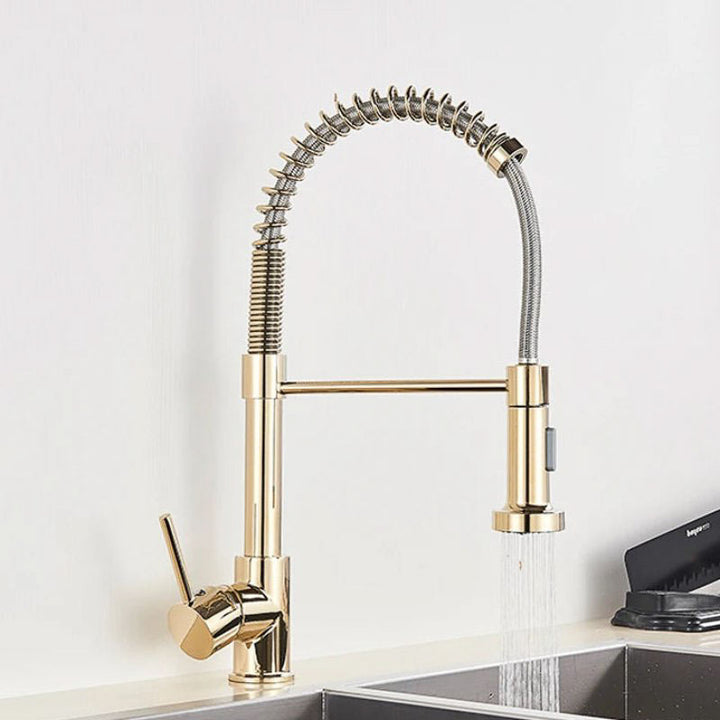 Gold kitchen tap with a flexible hose on a white background