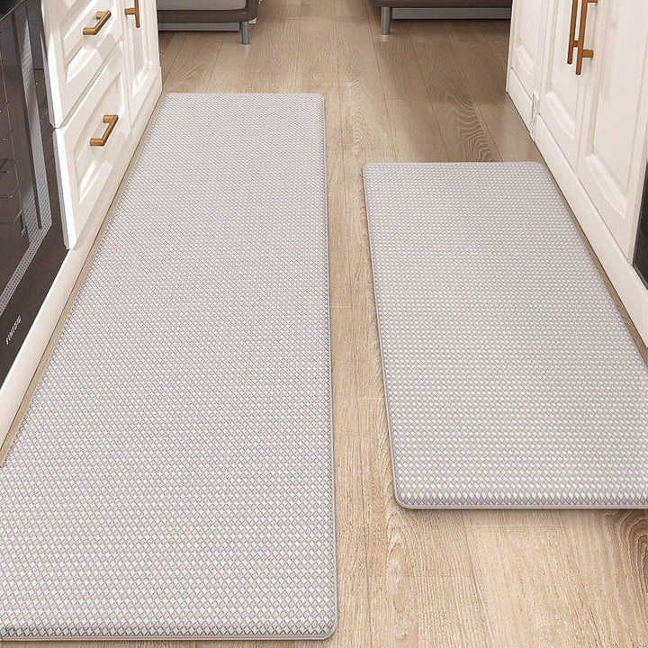 Two gray textured kitchen mats on a wooden floor with white cabinets in the background.