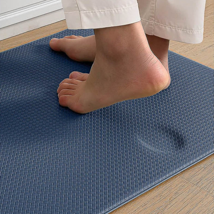 Person standing on a blue textured kitchen mat with feet visible