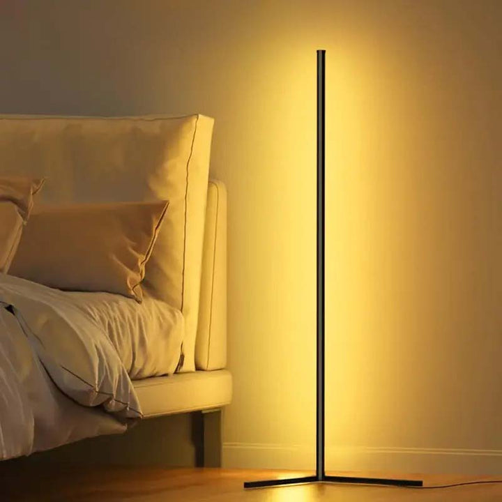 Modern floor lamp with remote casting a warm glow in a bedroom setting.