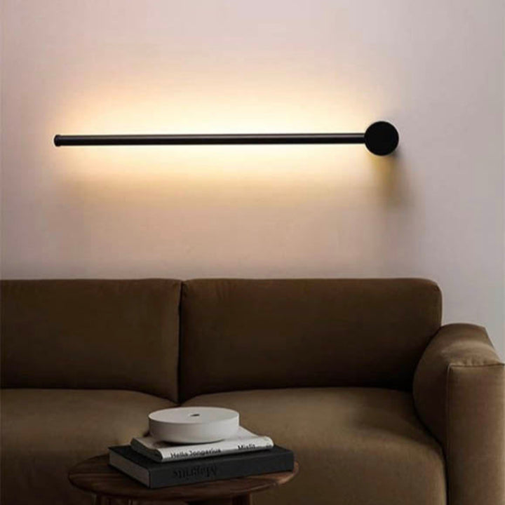 Modern vertical LED wall sconces with black base and soft white glow, mounted on a minimalist white wall.