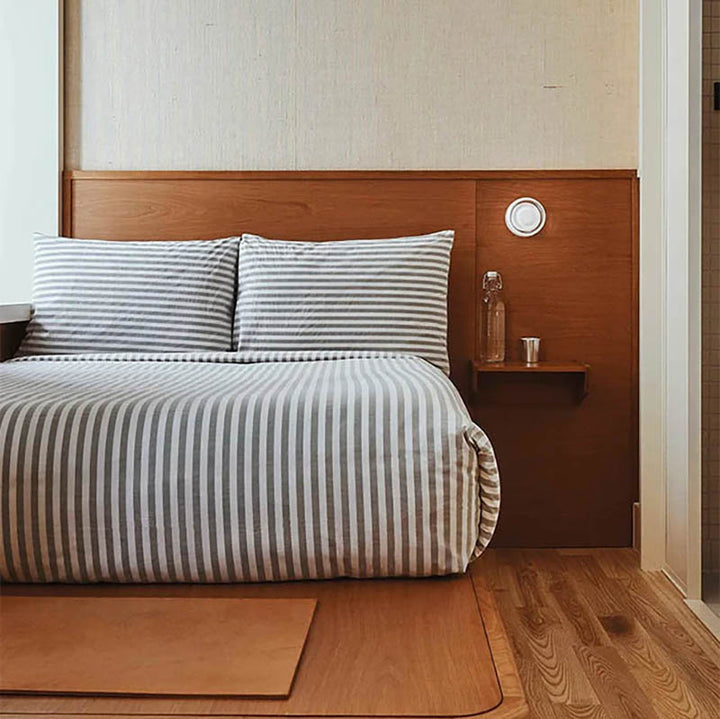 LYSEN Minimalist Metal Wall Light emitting warm glow in contemporary bedroom setting.
