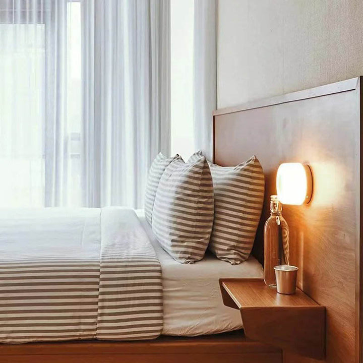 LYSEN Minimalist Metal Wall Light emitting warm glow in contemporary bedroom setting.