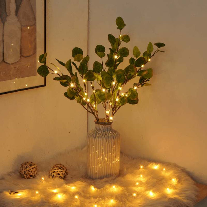 Fairy Light Olive Branch with warm twinkling lights in a striped ceramic vase, styled on soft faux fur with glowing accents.
