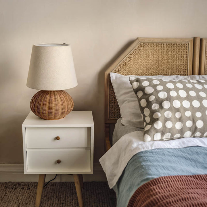 Small LUN rattan round bedside lamp on white nightstand, warm Nordic lighting in Scandi-style uk bedroom interior