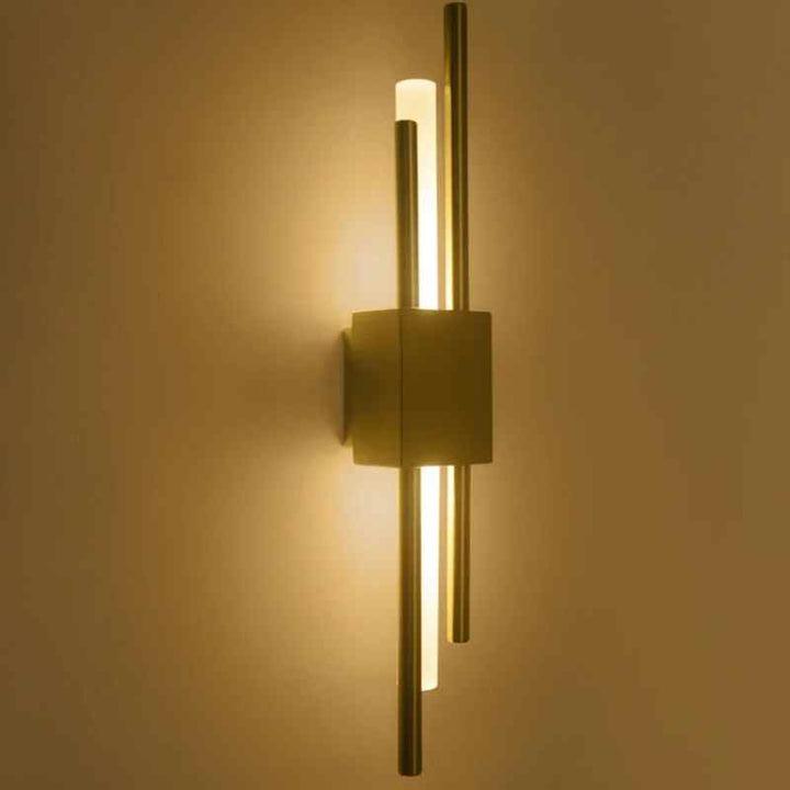Warm gold LED wall sconce with dual vertical rods emitting soft light on wall
