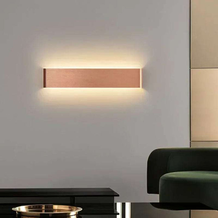 Copper finish LYST LED wall lamp on living room wall with warm glow for modern Scandinavian décor