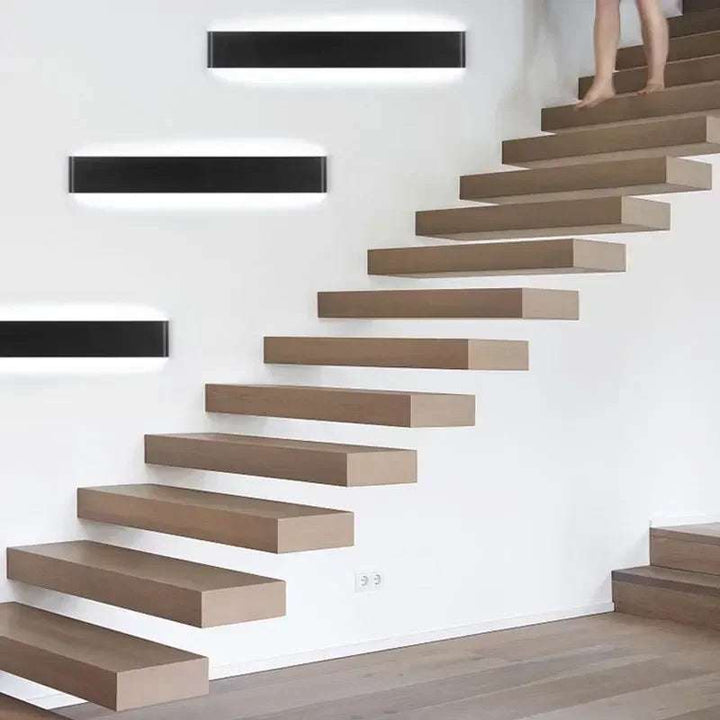 Black LYST LED wall lamps mounted along staircase, providing sleek Scandinavian hallway lighting