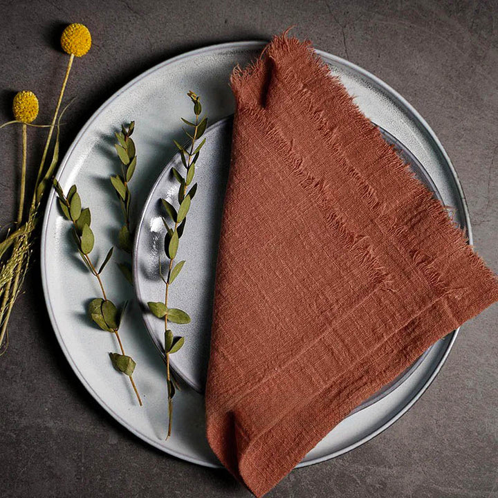 Terracotta cotton gauze napkin folded on ceramic plate with botanical accents, 41 × 41cm – soft and elegant for Scandinavian-style tables.