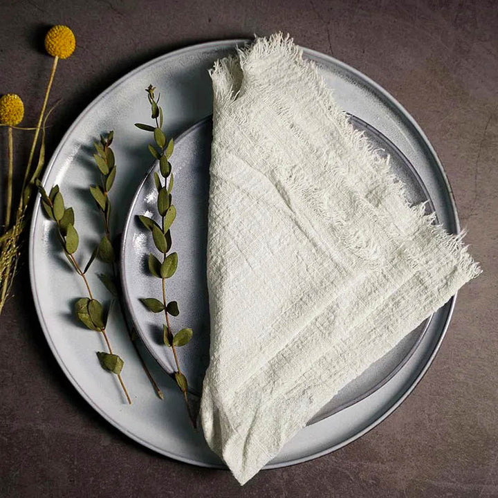 Off - white cotton gauze napkin folded on ceramic plate with botanical accents, 41 × 41cm – soft and elegant for Scandinavian-style tables.