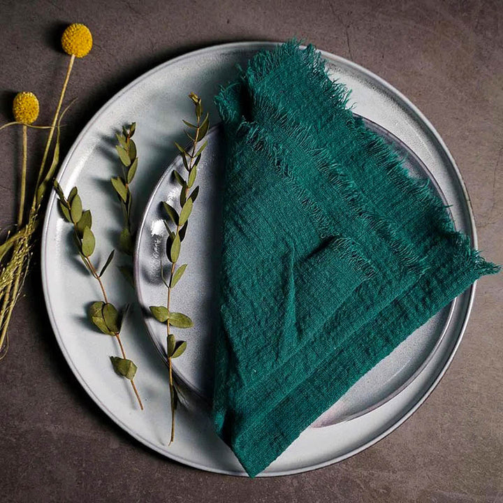 Green cotton gauze napkin folded on ceramic plate with botanical accents, 41 × 41cm – soft and elegant for Scandinavian-style tables.