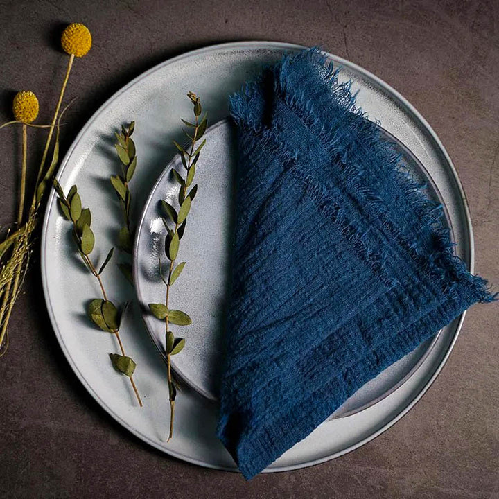 Blue cotton gauze napkin folded on ceramic plate with botanical accents, 41 × 41cm – soft and elegant for Scandinavian-style tables.