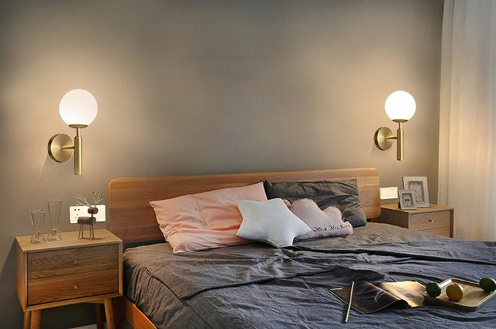 Two MAELKEBOLD modern glass ball wall lights, golden Nordic LED sconces in a bedroom.