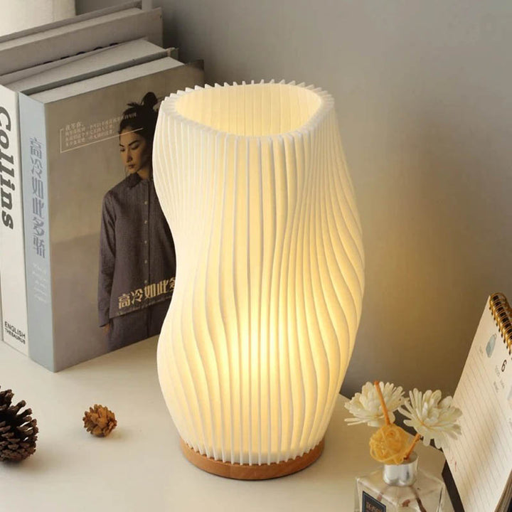 Warm glowing MOLLEN dimmable lamp placed beside books and ornaments for ambient shelf lighting.