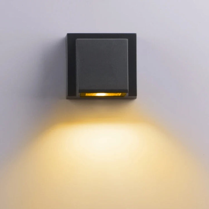 Square outdoor LED wall light fixture on a white wall
