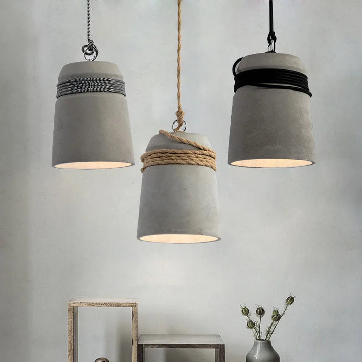 Three concrete pendant lights hanging against a plain background