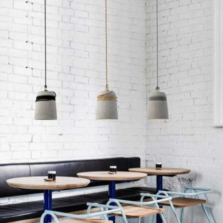 Modern cafe interior with pendant lights, tables, and chairs against a white brick wall.