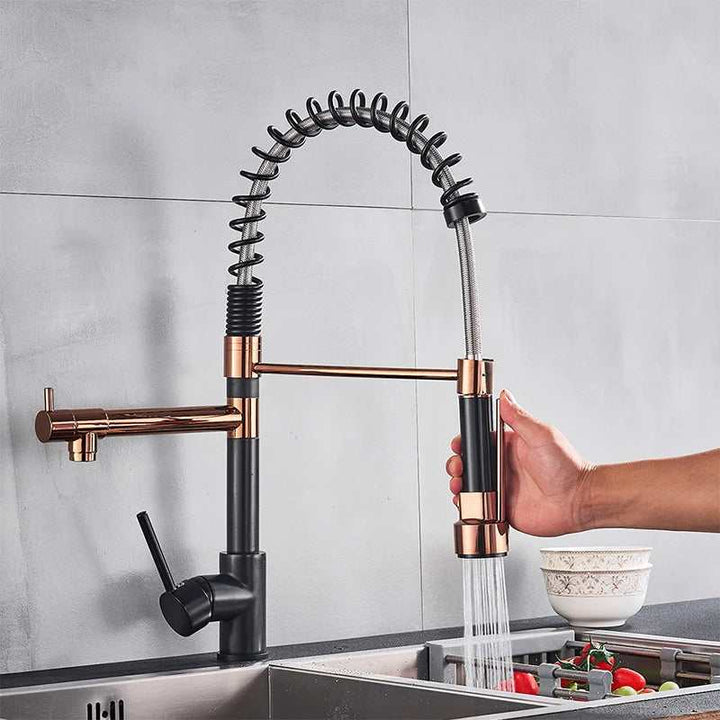 Modern black and copper pull-down kitchen faucet with industrial spring design, handheld sprayer running water into sink.