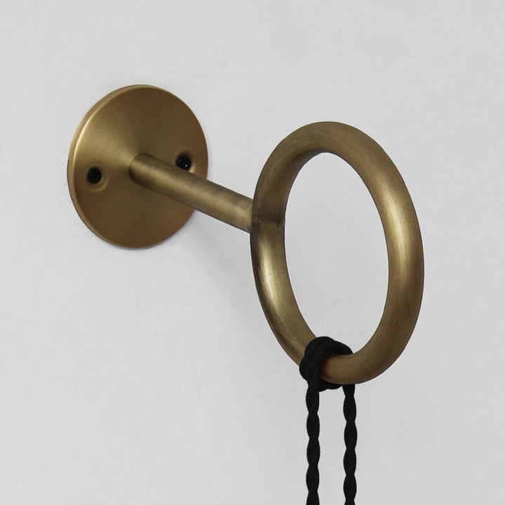 Brass curtain rod holder with a black cord on a white background