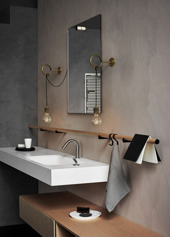 Modern bathroom with a sink, mirror, and towel rack against a gray wall.