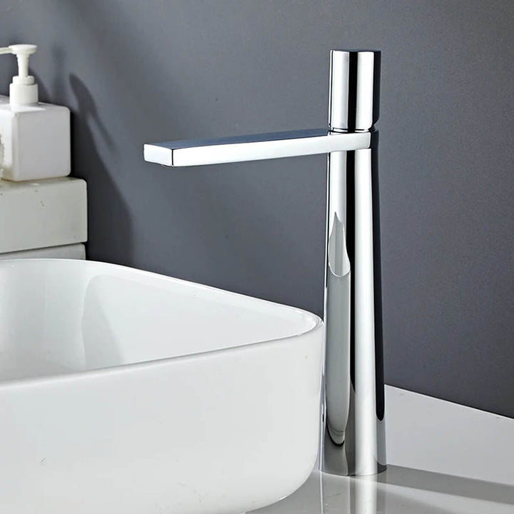 A modern high arch basin faucet with a chrome finish, positioned above a white sink, with a minimalist single-handle design.