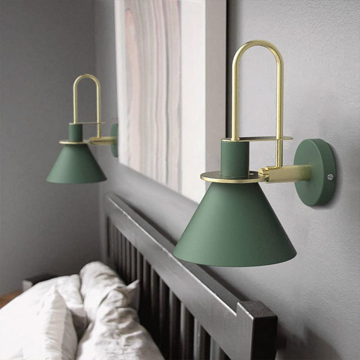 Green wall sconces with gold accents on a gray wall above a bed.
