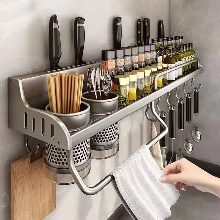 Kitchen wall organizer with knives, bottles, and utensils on a gray tiled wall.