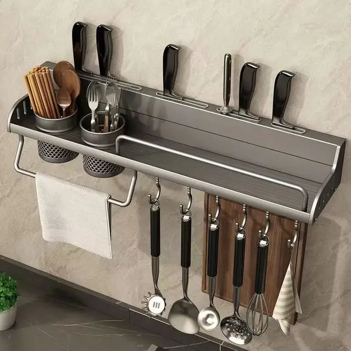 Wall-mounted kitchen organizer with utensils and cutlery on a tiled wall.