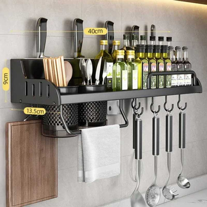 Wall-mounted kitchen organizer with utensils, bottles, and cutting board on a gray tiled wall.