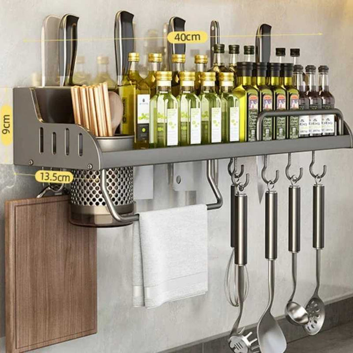 Wall-mounted kitchen organizer with utensils, bottles, and cutting board on a gray tiled wall.