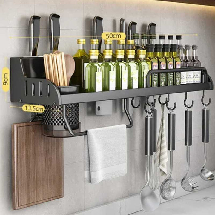 Wall-mounted kitchen organizer with utensils and bottles on a tiled wall.