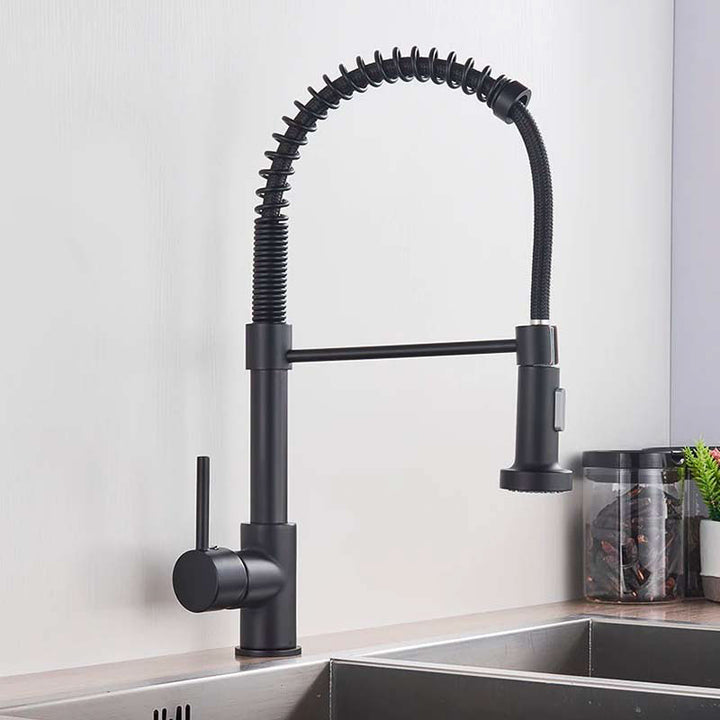 Black kitchen tap with flexible hose on a white wall background