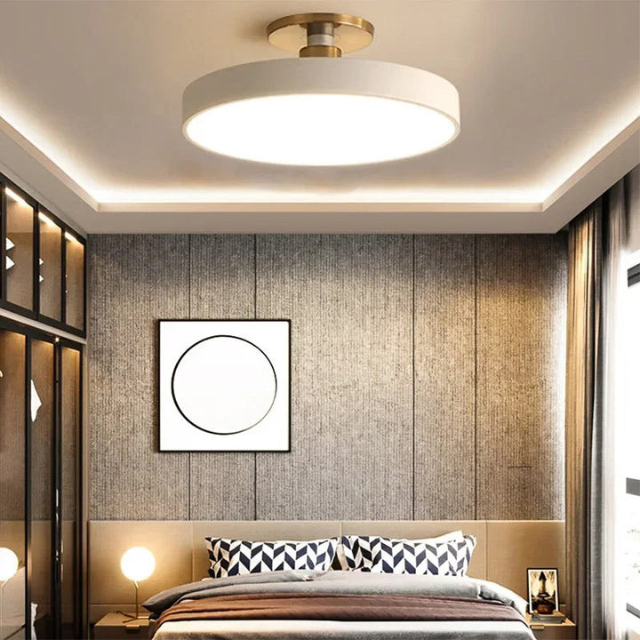 Modern bedroom with ceiling light fixture, wall art, and bed with striped pillows.