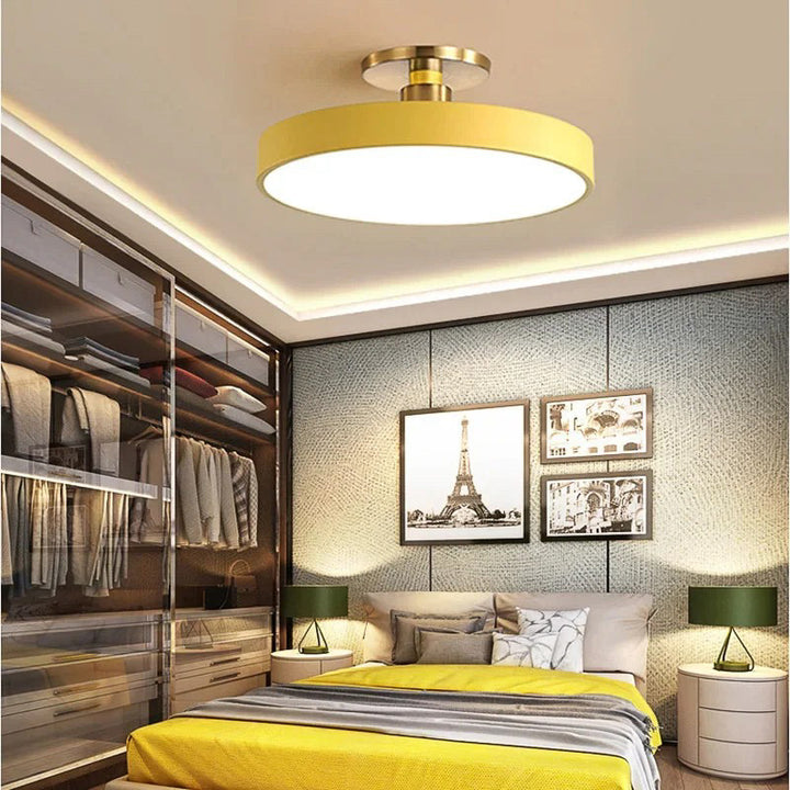 Modern bedroom with yellow ceiling light fixture, bed, and wall art.
