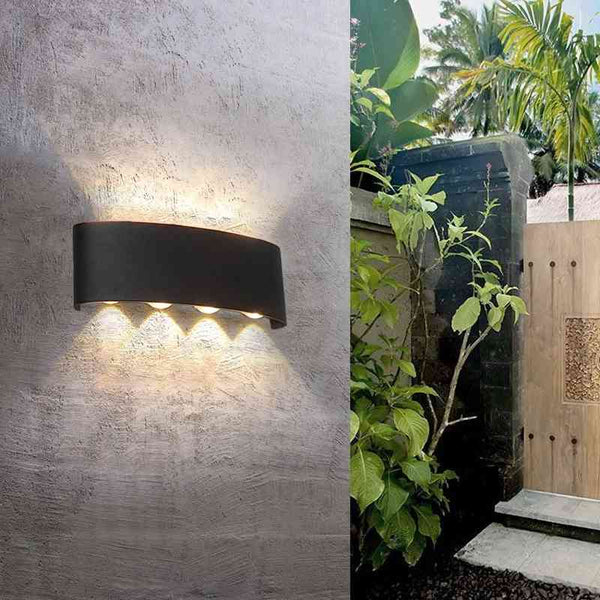 Black aluminum modern LED wall light on textured wall, blending with outdoor garden decor.