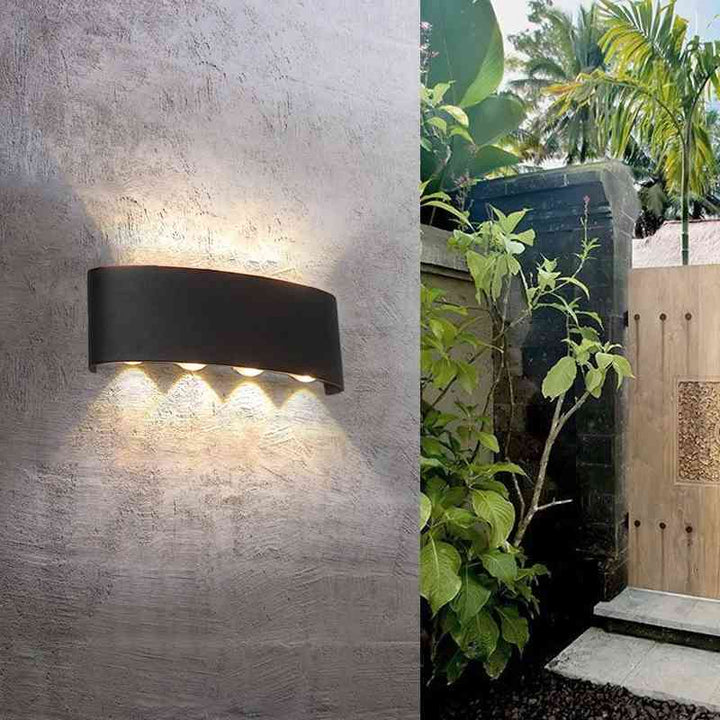 Black aluminum modern LED wall light on textured wall, blending with outdoor garden decor.