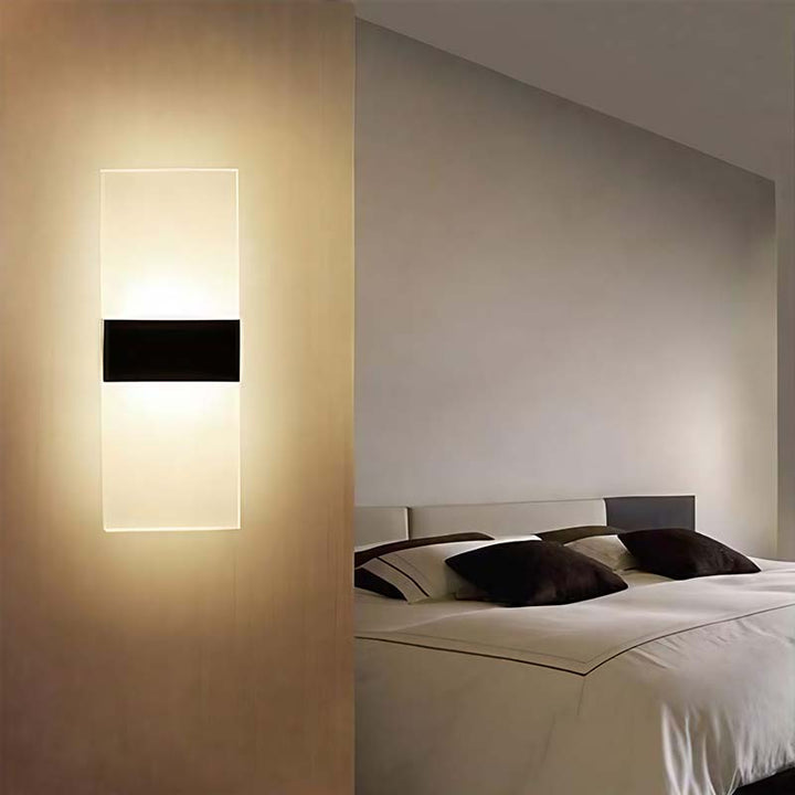 Modern wall sconce in a bedroom setting with a bed and neutral walls.