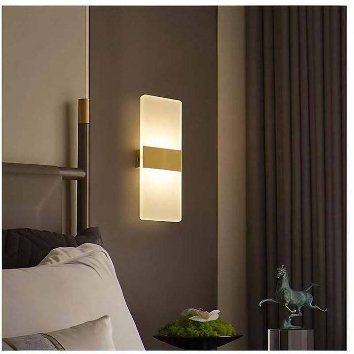 Modern wall sconce in a bedroom setting with a bed and decorative items.
